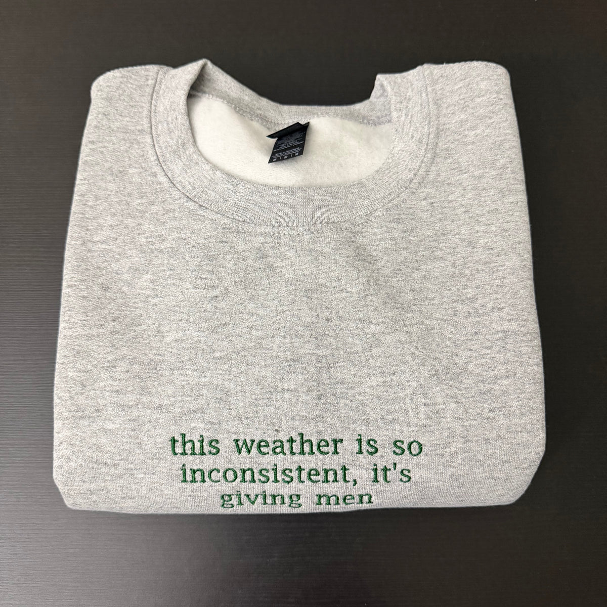 “This weather is so inconsistent, it’s giving men” embroidered sweatshirt