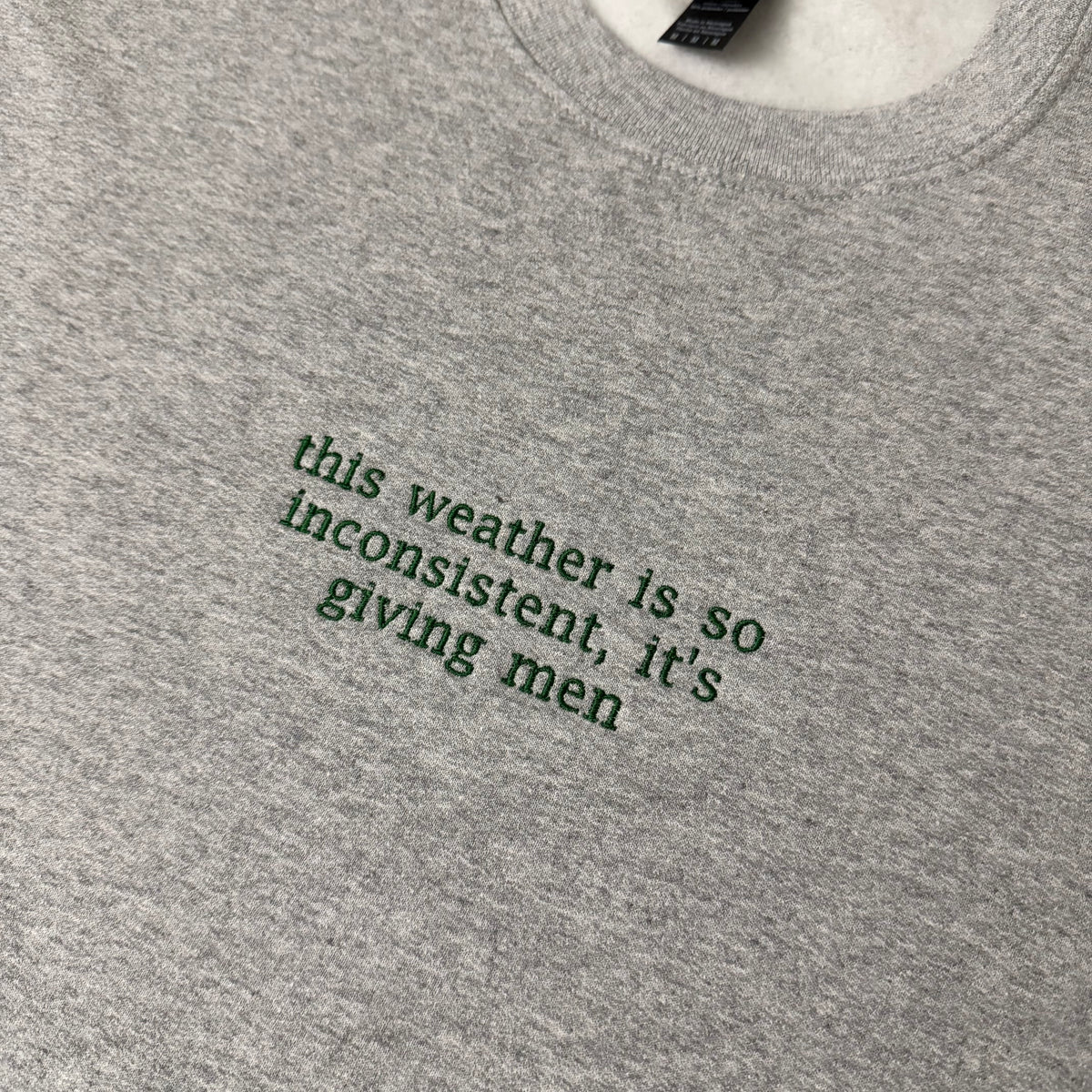 “This weather is so inconsistent, it’s giving men” embroidered sweatshirt