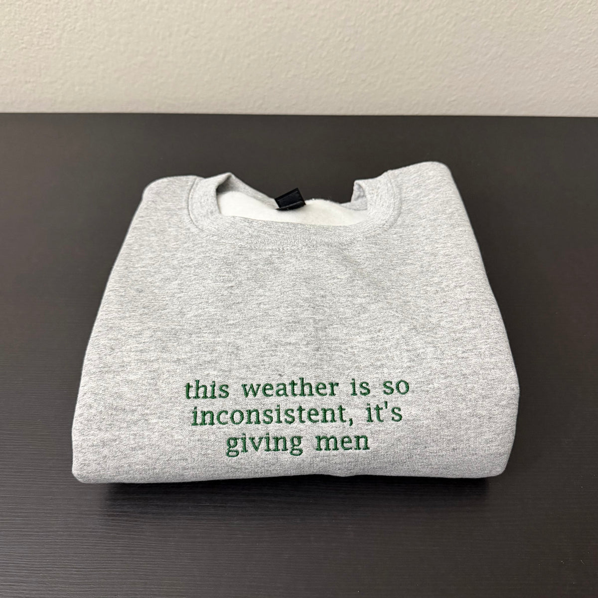“This weather is so inconsistent, it’s giving men” embroidered sweatshirt